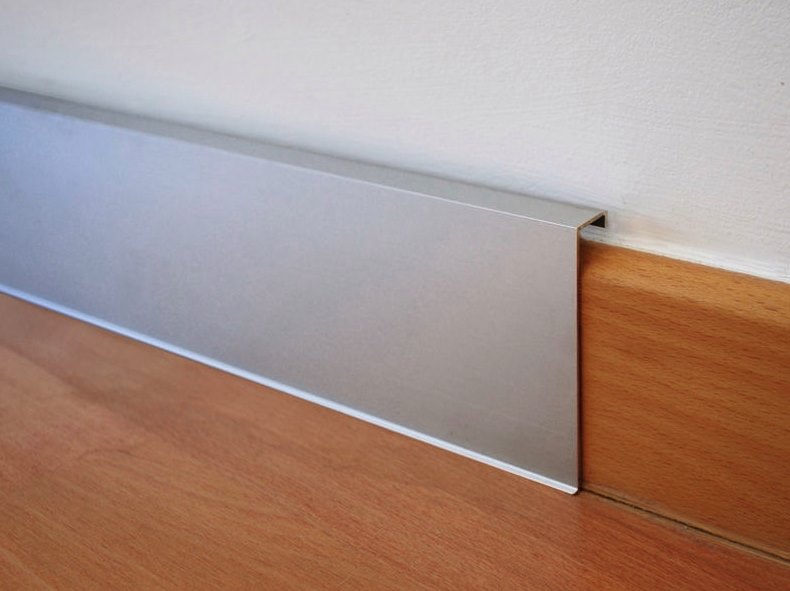 Sleek aluminum baseboard beautifully offsets wood flooring