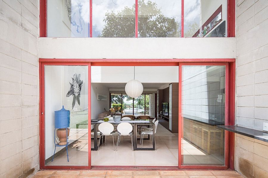 Sliding glass doors with bright red metallic frames for the concrete Brazilian home