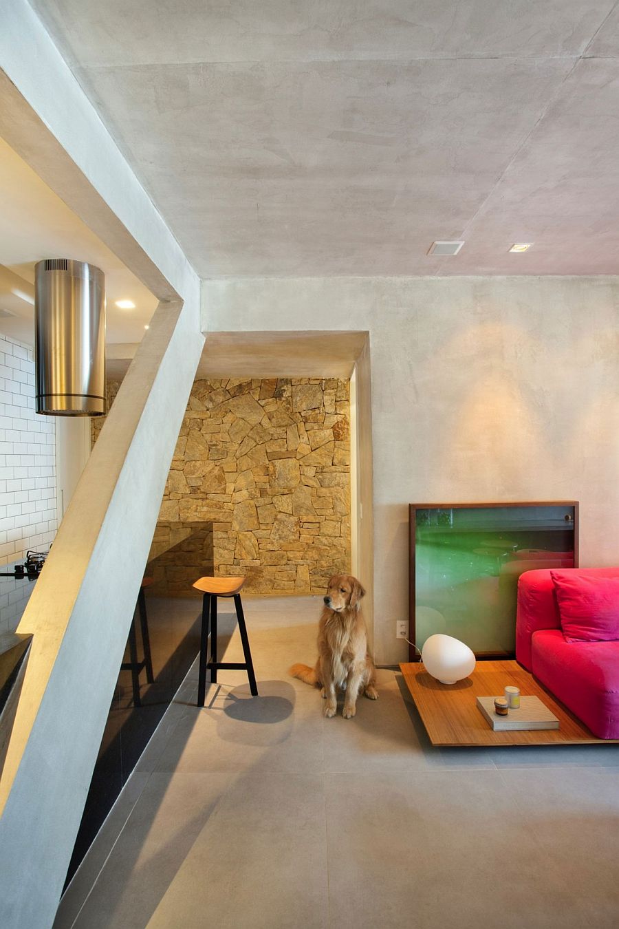 Stone wall in the kitchen adds a contrasting texture to the concrete interior