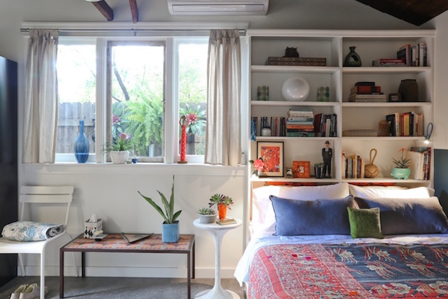 Tall white bookshelf with accessories behind bed