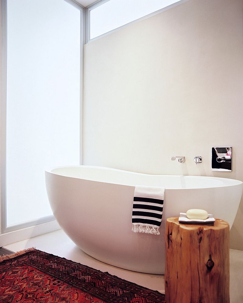 Tree stump stool used as side table next to the bathtub