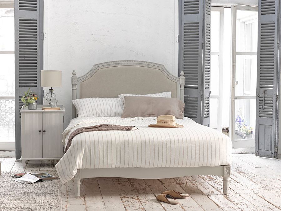 Weathered look of the flooring, shutters in gray and vintage bed usher in the shabby chic style