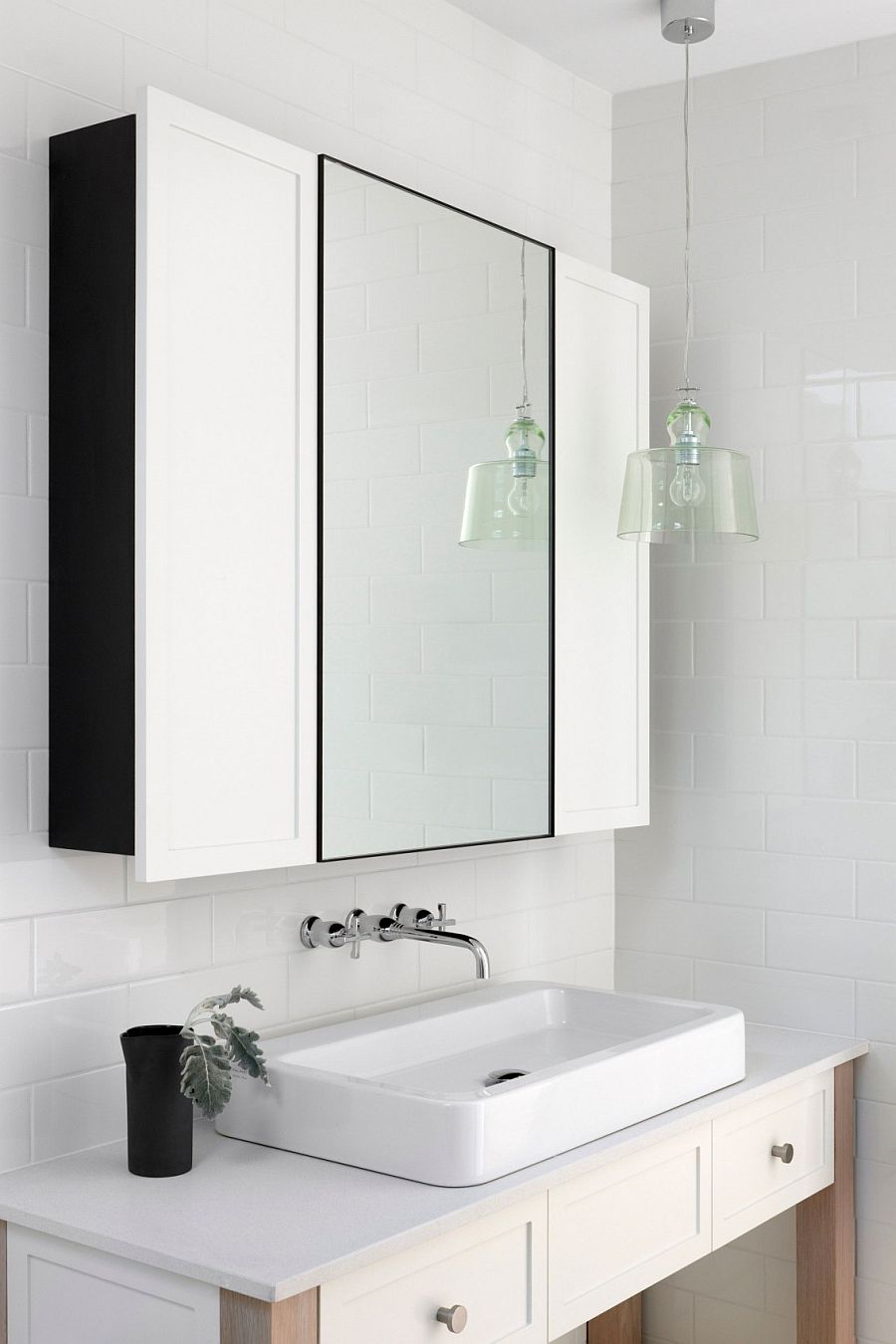 White vanity and medicine cabinet of the becah style bathroom with a hint of black