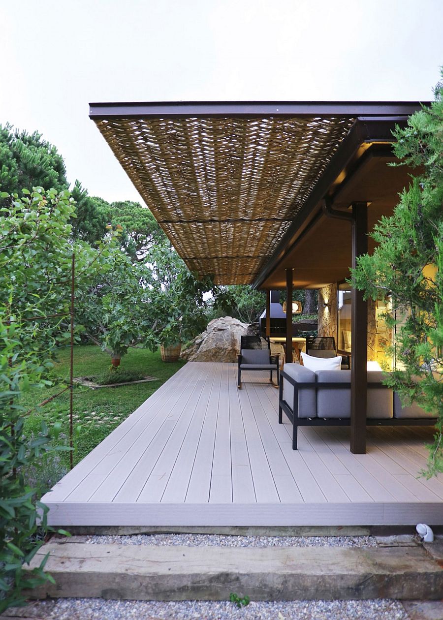 Wooden deck, wicker and iron pergola extend the living area into the lush green garden