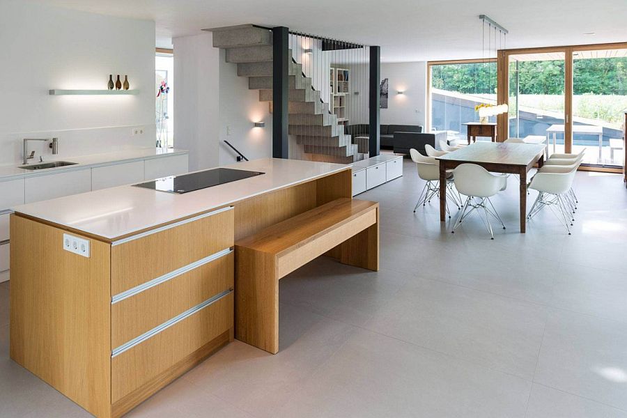 Wooden kitchen island with a stone worktop and a wooden becnh for breakfast bar