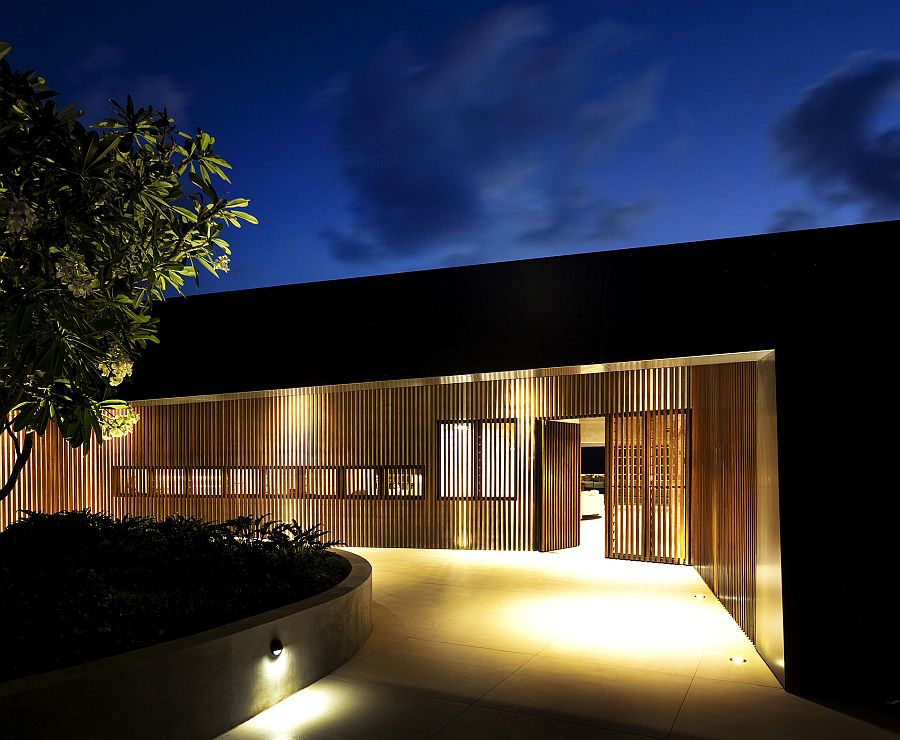 Wooden slats and brilliant lighting create a private entrance to the luxurious home