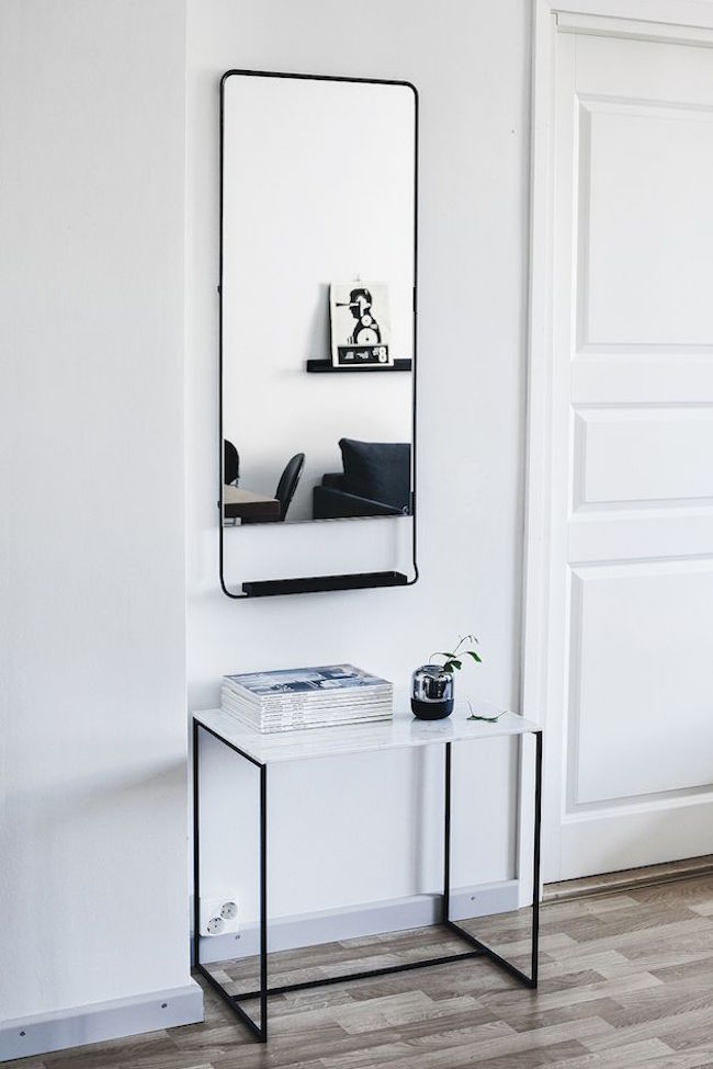 A Scandinavian entryway with striking charcoal tones for the mirror and table