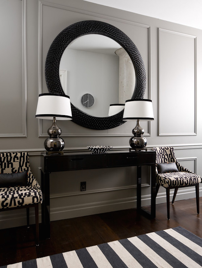 Black and white entryway with large round mirror