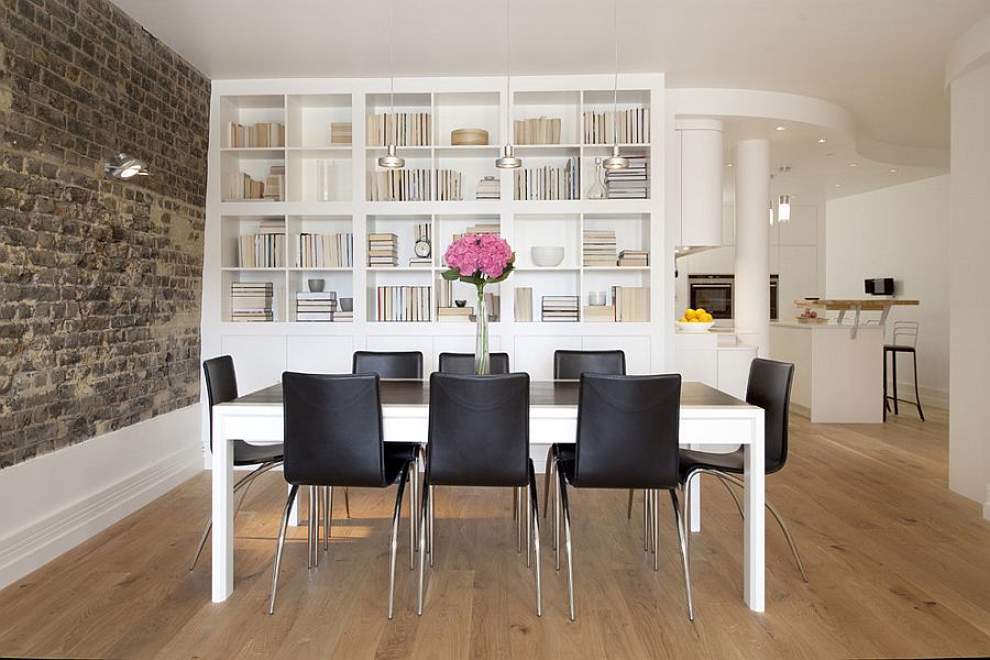 Brick wall brings brilliant textural contrast to the refined dining room with bookshelves