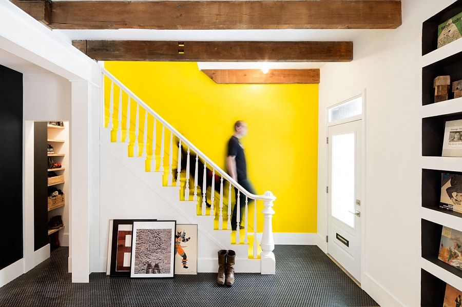 Bright accent wall in yellow stands out in the black and white interior of the Quebec home