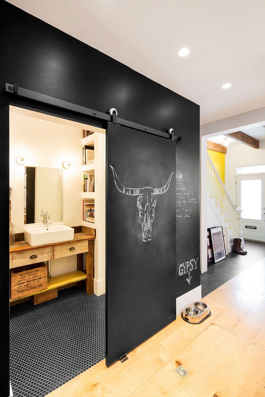 Chalkboard wall and sliding door hide the tiny bathroom on lower level