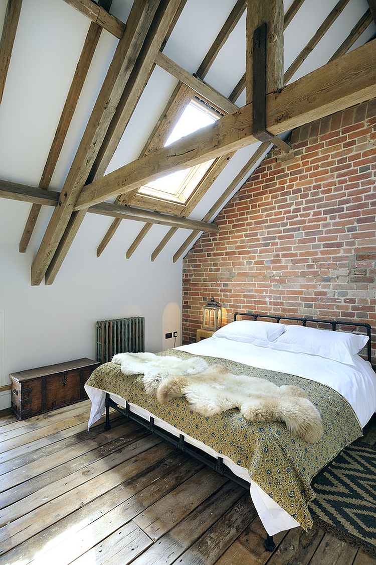 Farmhouse style bedroom with wooden ceiling beams, skylight and exposed brick wall [Design: PAD studio]