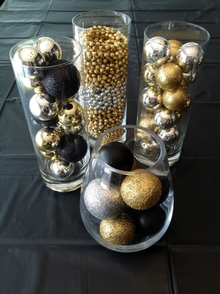 Gold, black, and silver Christmas ornaments in glass cylinders