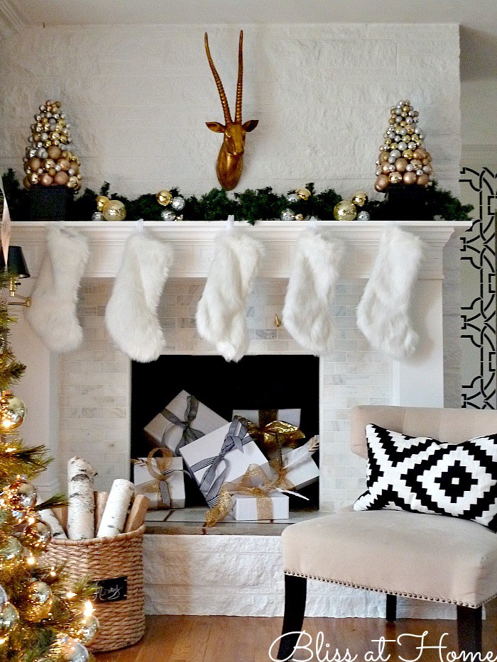 Holiday mantel with white stockings and gifts piled in fireplace