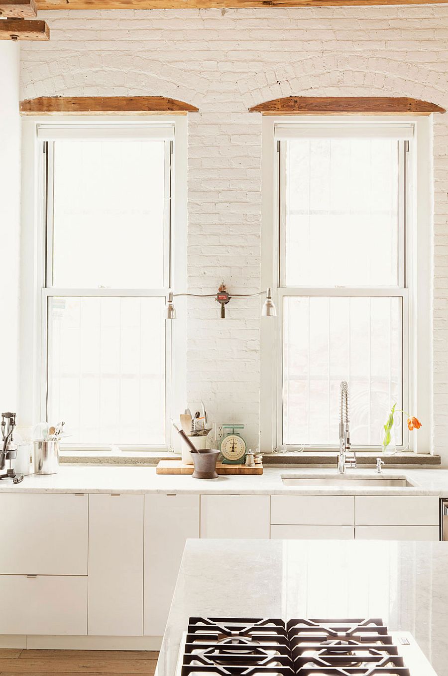 Kitchen in white with exposed brick walls and large windows