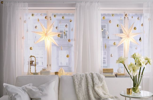 Large bright star lights hung with smaller ornaments in window