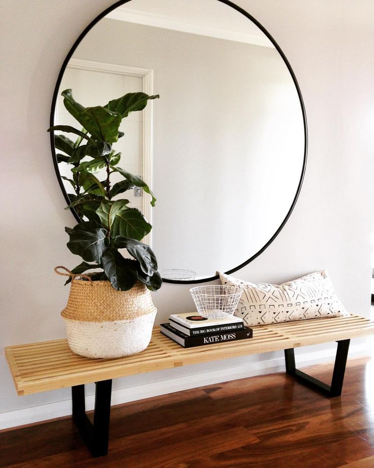 Large round mirror above a wood bench