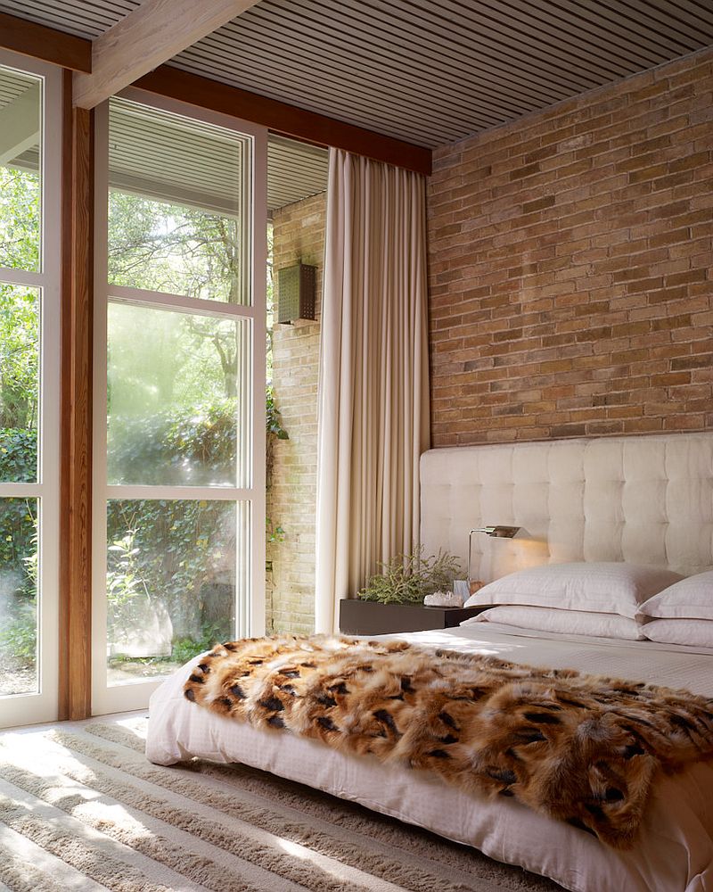 Midcentury modern bedroom employs cozy bedding and rug to contrast exposed brick wall [From: Kisabeth Furniture]