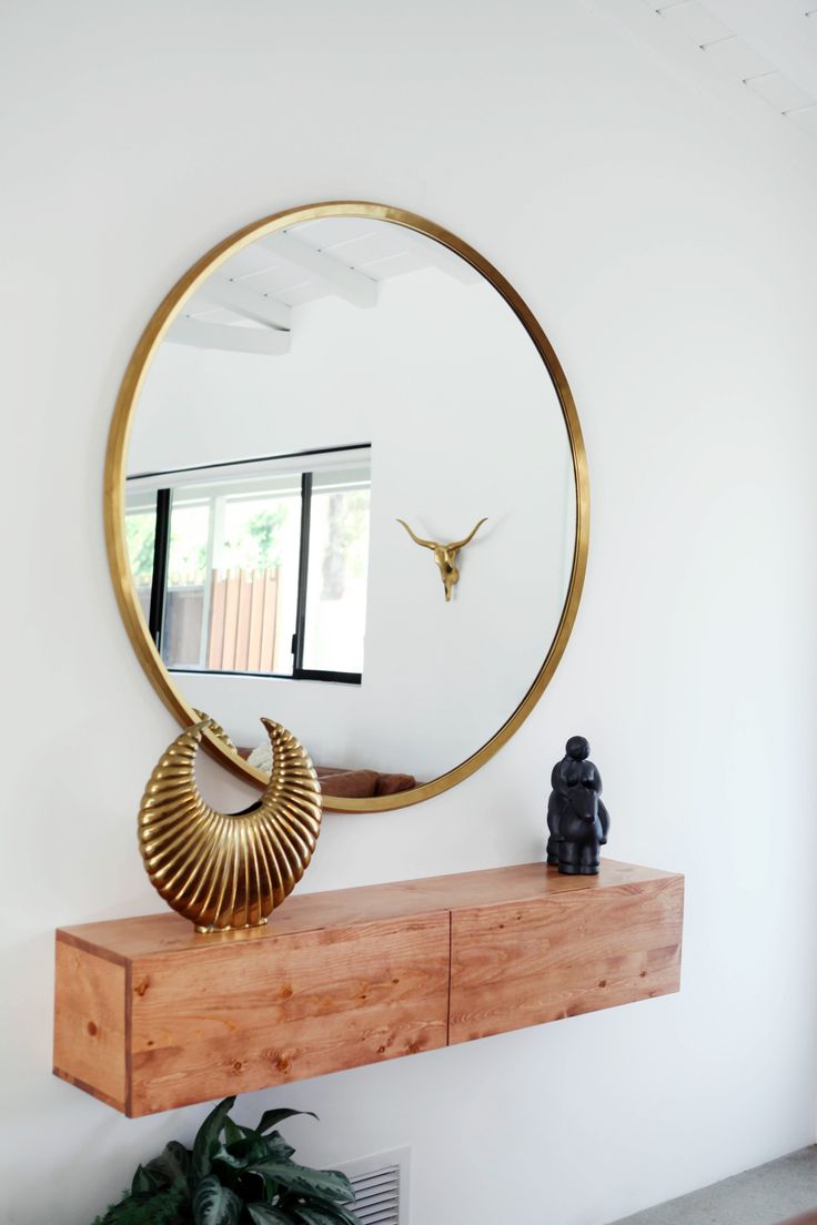 Minimal entryway decor with a large round mirror with gold frame