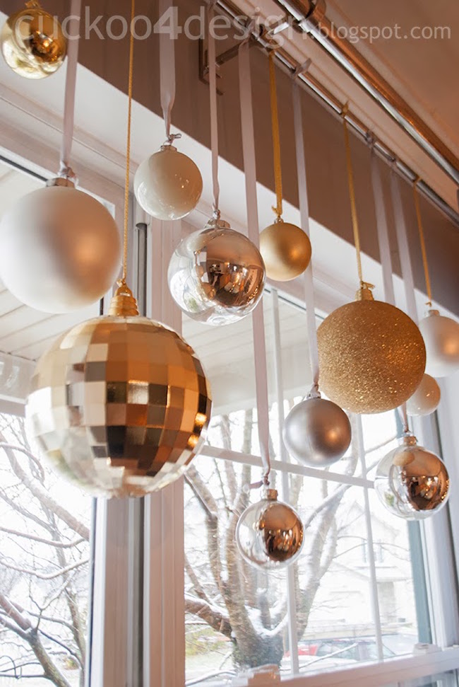 Silver and gold glass ball ornaments hung from matching ribbon in window