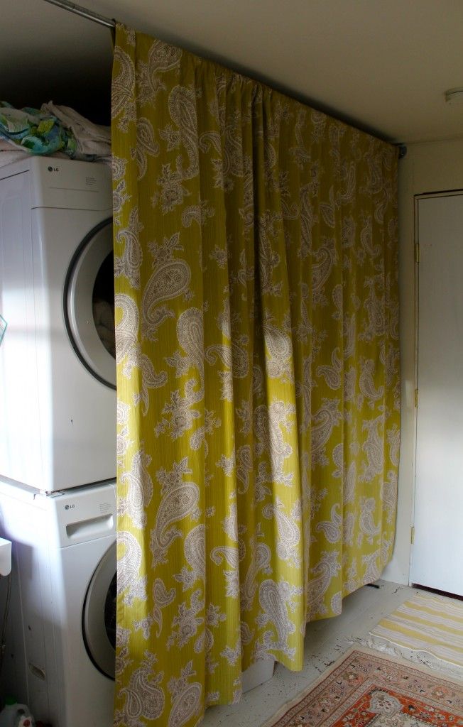 Stacked washer and dryer hidden by a yellow paisley curtain