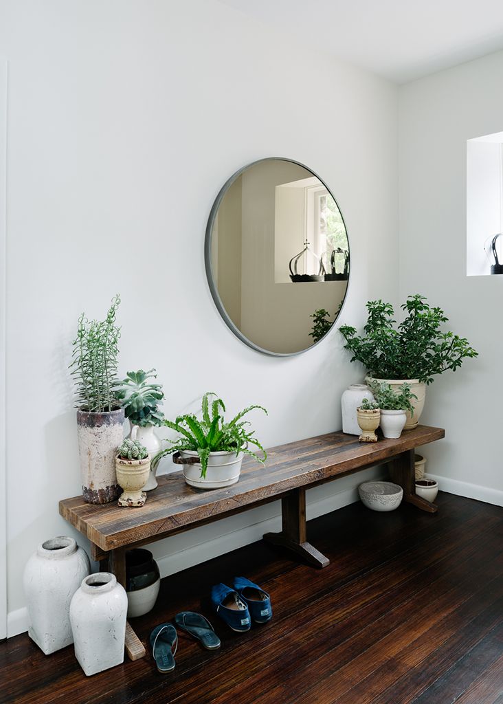 Stunning entryway setup with rustic bench, round mirror, and lots of plants