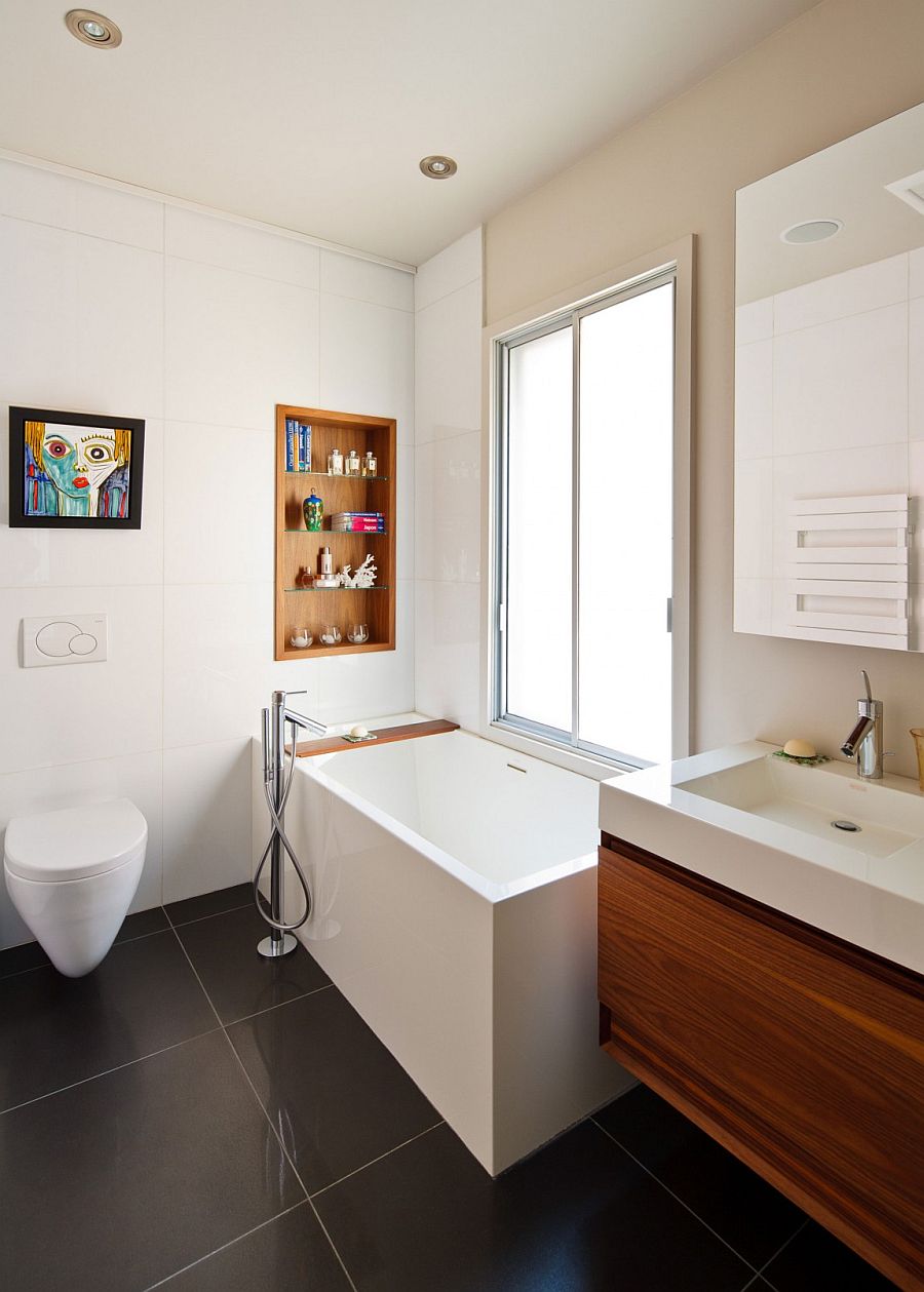 Tiny bathtub with a built-in wooden shelf next to it for bathroom accessories