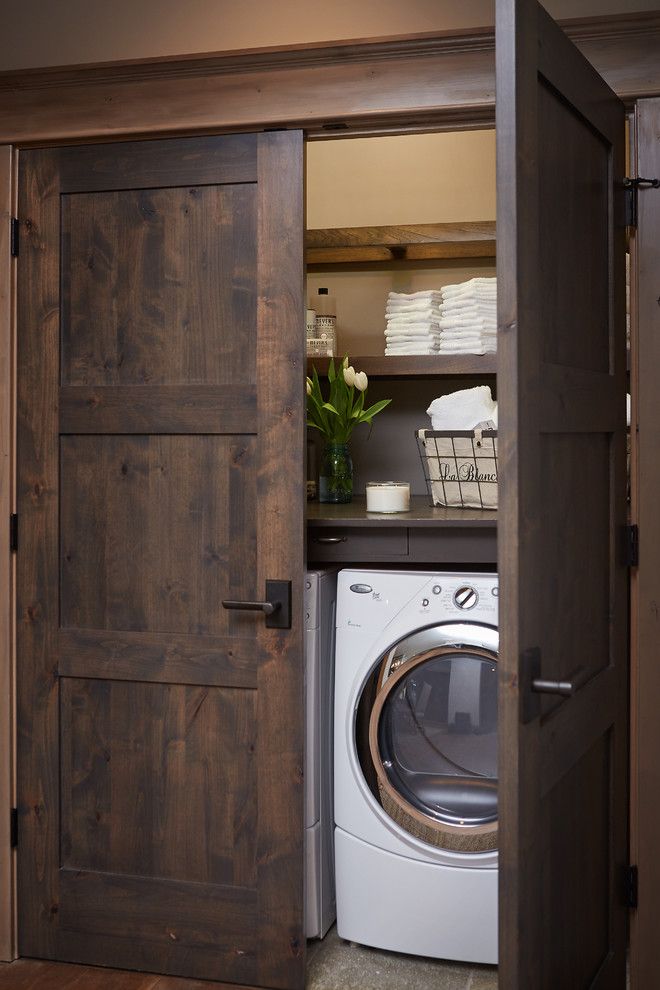 Washer and dryer hidden in closet with beautiful dark wooden doors