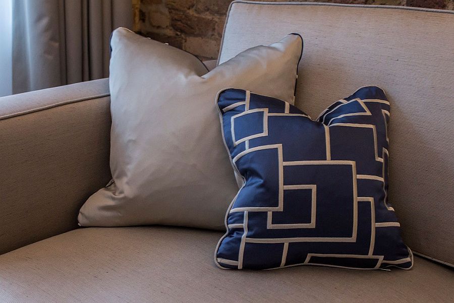 Accent piilows and couch in the living room enhance the blue-gray color scheme of the apartment