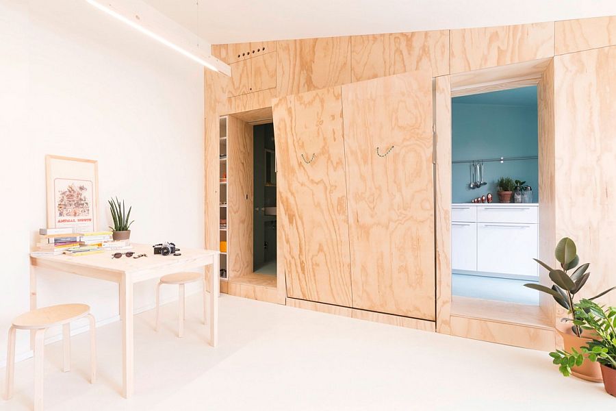 Active doors and wooden walls hide the kitchen, bed and other spaces