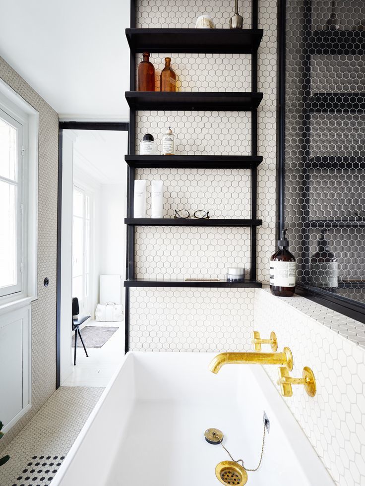 Black shelves installed on wall beside bathtub in Parisian apartment