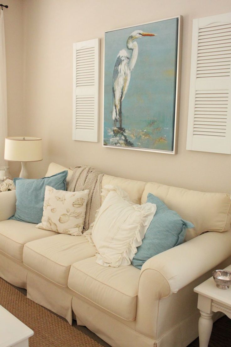 Coastal-themed living room with shutters on either side of artwork