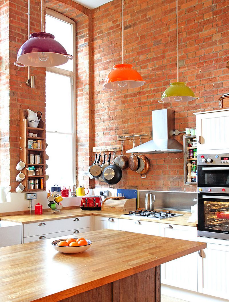 Eclectic kitchen with colorful lighting and brick wall backdrop [Design: Avocado Sweets Interior Design Studio]