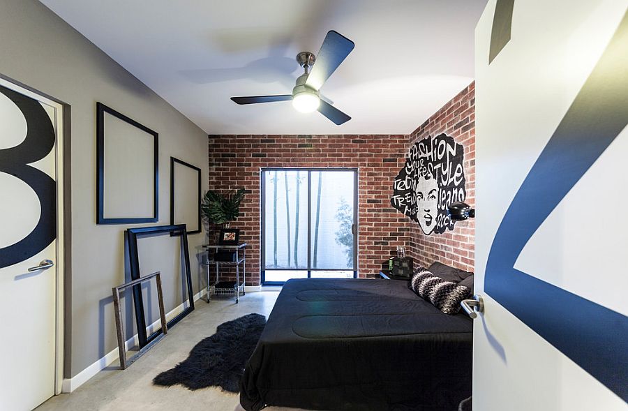Exposed brick wall, grafitti and giant empty picture frames come together to fashion an exclusive bedroom
