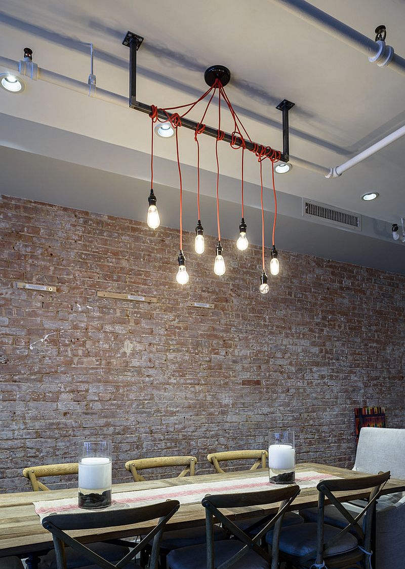 Exposed brick wall, lighting and wooden table for an industrial loft-inspired dining room