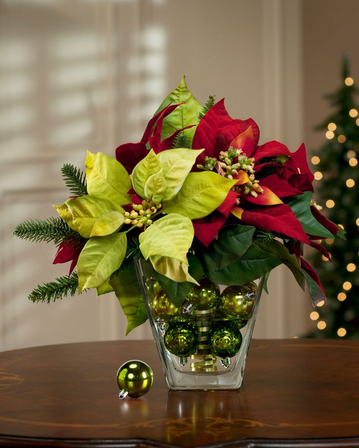 Faux poinsettia arrangement in glass vase with Christmas ball ornaments