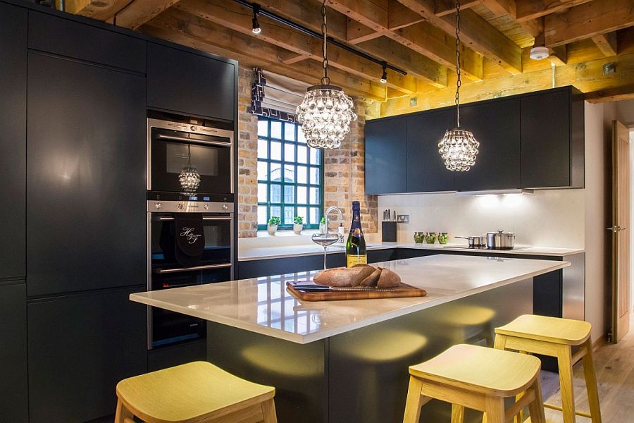 Gorgeous pendant lights add to the glitter of the bluish-gray kitchen with brick wall