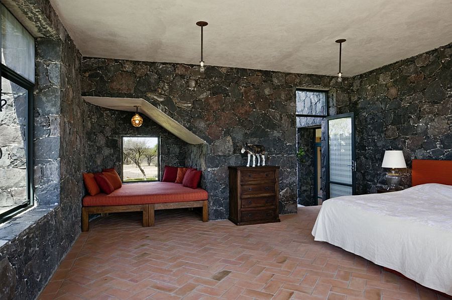 Mediterranean bedroom showcases terracotta tiles and dark stone walls [Design: David Howell Design]