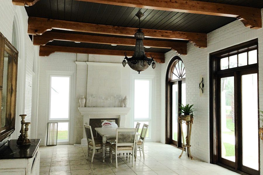 Mediterranean sunroom with black ceiling, exposed wooden beams and a lovely chandelier [Design: William Caswell Architect]