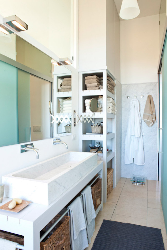 Shelving replaces a section of the wall beside this bathroom's vanity