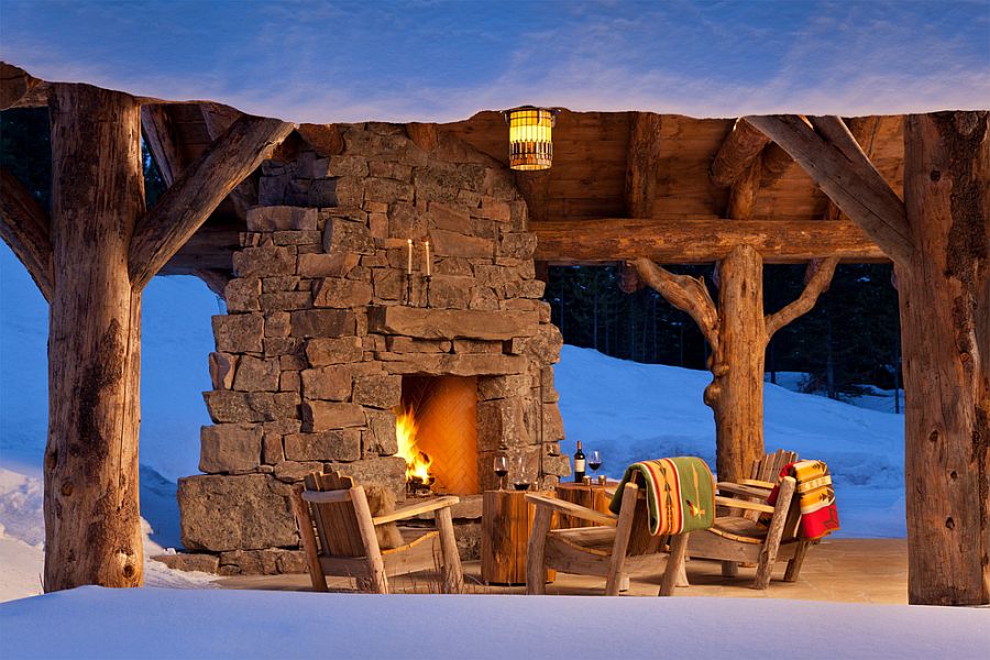 Stump side tables, wooden chairs and cozy stone fireplace make a magical patio at Spanish Peaks Cabin