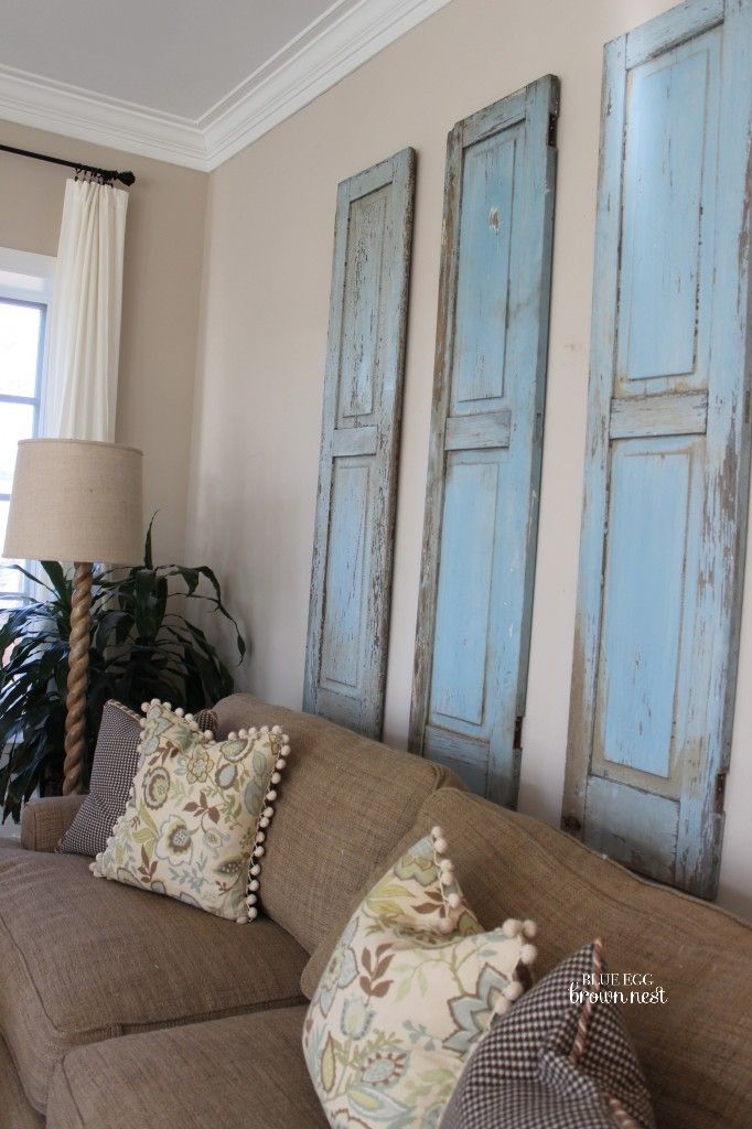 Three rustic blue shutters in a living room above a sofa