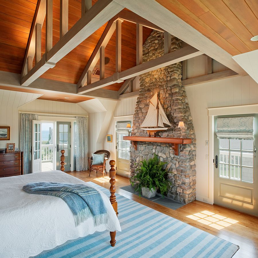 Traditional stone fireplace used as a decorative element in the beach style bedroom [Design: Dennis Moffitt Painting]