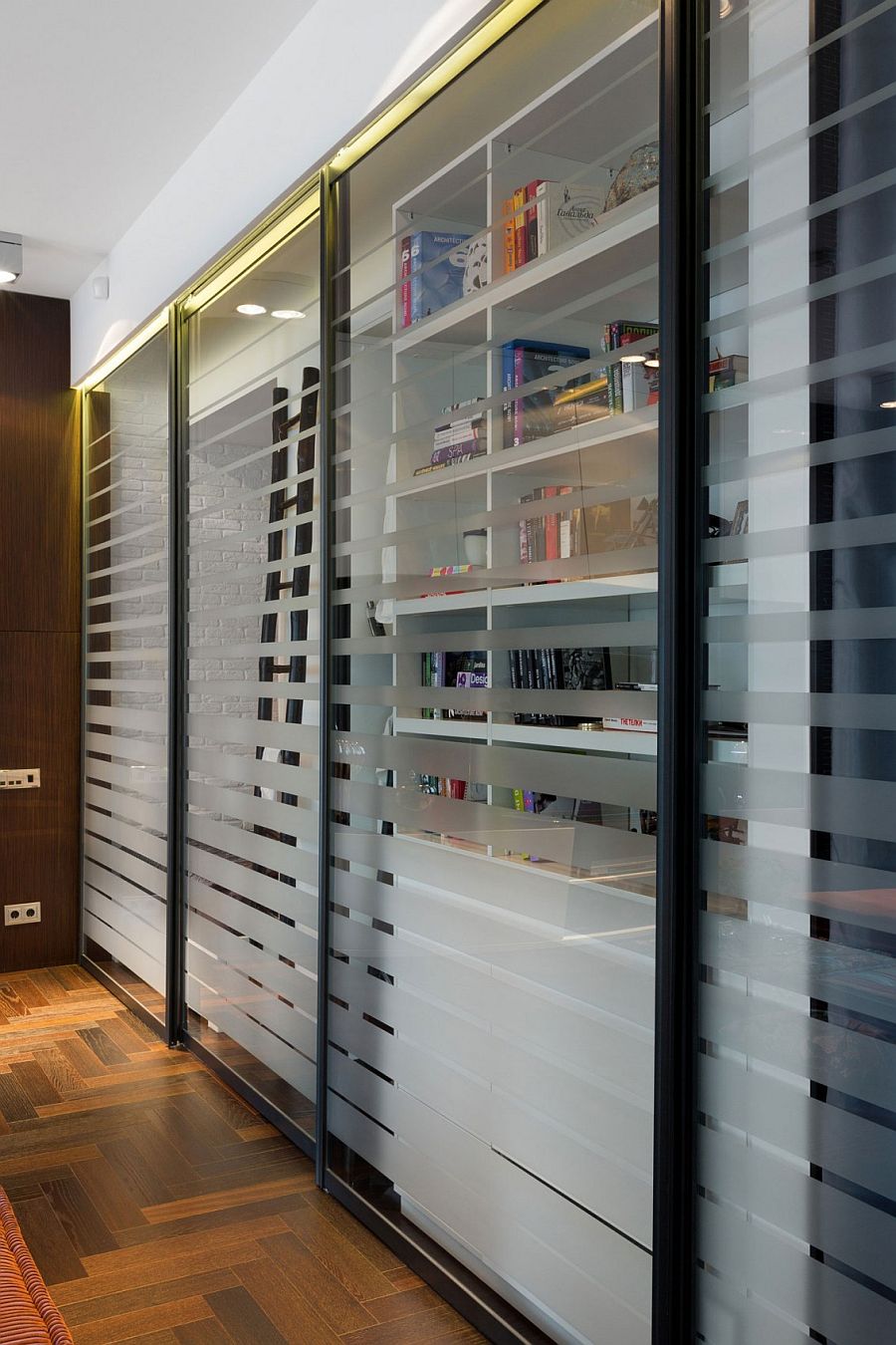 Wall of books behind the sliding glass doors shapes the tiny home library