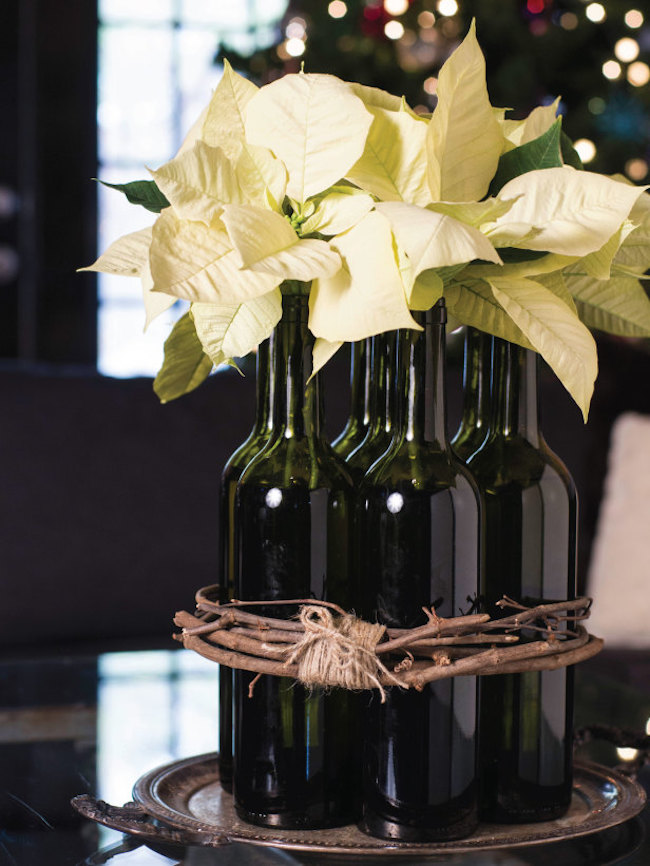 White poinsettias displayed in wine bottles