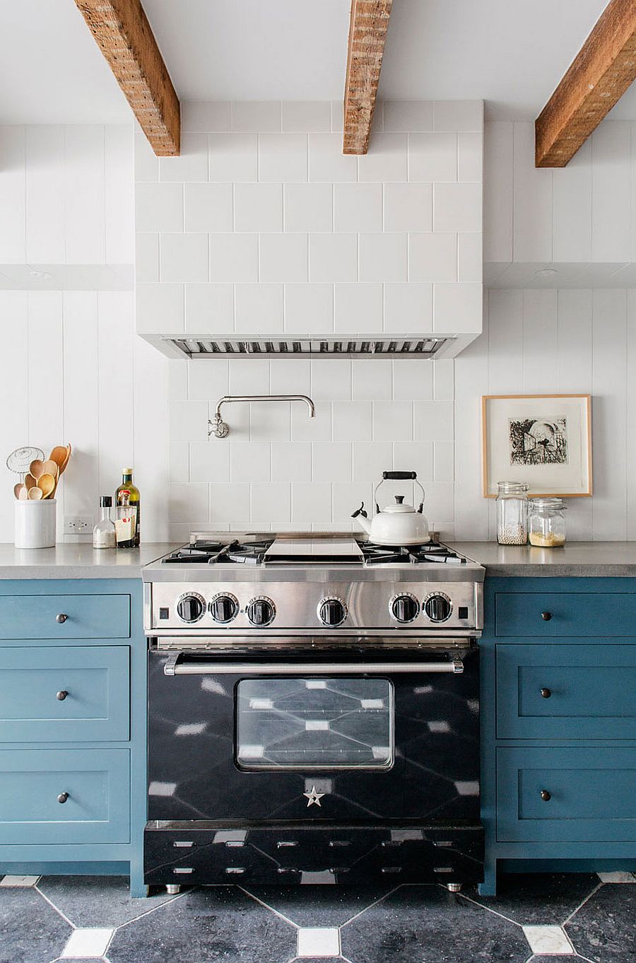 Gorgeous kitchen range in black stands out thanks to the neutral backdrop and blue cabinets