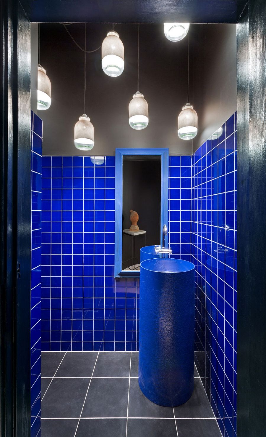 Massive industrial pipe turned into custom sink inside the small bathroom with bright blue walls