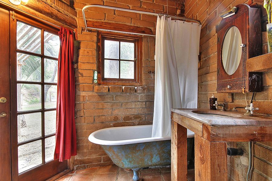 Small rustic bathroom with weathered bathtub and brick backdrop [From: Julie Angelos]