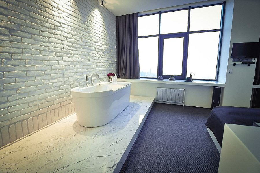 White brick wall fits in seamlessly with the contemporary vibe of the master bedroom with bathtub