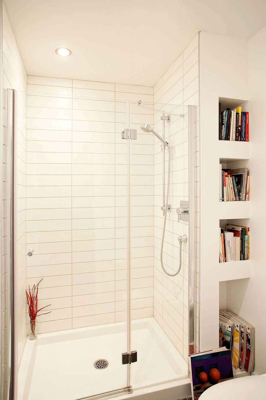 White shower area with small niches next to it that store books and magazines